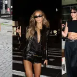 Tres mujeres con atuendos negros, una con botas de cuero y shorts, otra con chaqueta brillante y shorts, y la tercera con top corto y pantalones anchos, evocan un estilo glam rock.