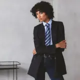 Persona andrógina con traje a rayas, camisa azul y corbata a juego.