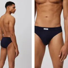 Hombre en perfil mostrando un slip azul marino. Primer plano del mismo slip, con etiqueta.