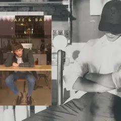 Un joven con un armario cápsula hombre, sentado en un café, reflexiona.