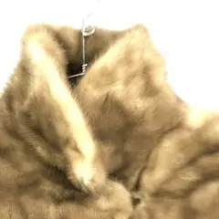 Abrigo de piel color caramelo, digno de una mob wife, colgado en una percha.