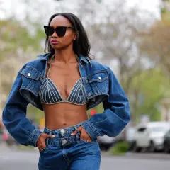 Mujer con gafas de sol luce un conjunto de **denim on denim**: chaqueta corta y sujetador de pedrería, combinados con jeans.