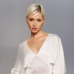 Iris Law, con su corte de pelo rubio platino y un top blanco de seda, posa con una mirada intensa.