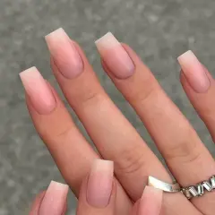 Manos con uñas naturales bonitas en forma cuadrada, con un degradado sutil de rosa pálido a transparente.