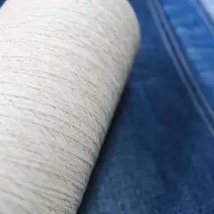 Rollo de hilo crudo sobre tela vaquera azul. El hilo es la base del denim, un tejido con un rico significado cultural.