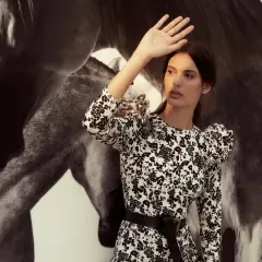 Inés Domecq, con su vestido floral, se protege del sol junto a la imponente silueta de un caballo.