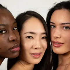 Tres mujeres de diferentes etnias, una con piel **color negro**, se miran a la cámara con labios brillantes.