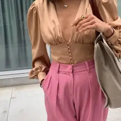 Elegante blusa beige satinada con pantalones rosa vibrante. Un look chic que demuestra los colores que combinan con el beige.