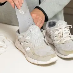 Man removes insole from dirty white Nike sneakers. Learn como quitar desteñido en zapatillas blancas.