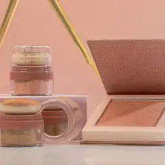 Dos envases de iluminador sueltos y un iluminador en polvo compacto, todos con tonos dorados y rosados, listos para dar luz a tu rostro.