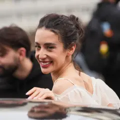 La belleza de Paula Badosa se refleja en su sonrisa radiante, con el cabello recogido y un vestido blanco delicado.
