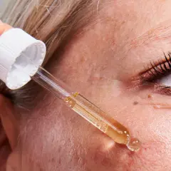 Una mano aplica un suero con un gotero sobre la piel. Descubre para qué sirve el retinol y cómo puede mejorar tu piel.
