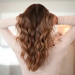 Melena castaña con ondas surferas, un estilo desenfadado y natural que realza la textura del cabello.