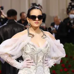 Rosalía deslumbrante en la Met Gala, con un vestido blanco adornado y gafas de sol audaces.