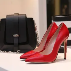 Elegantes zapatos rojos brillantes junto a un bolso negro. Un zapato a rayas blancas y negras se ve a la izquierda.