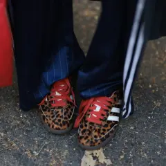 Zapatillas tendencia con estampado de leopardo y cordones rojos, combinadas con pantalones de raya diplomática.