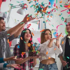 Jóvenes celebran un cumpleaños con confeti y pastel. ¡Una fiesta divertida para saber como vestir para un cumpleaños!