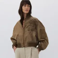 Mujer posando con una bomber marrón con bordado floral. Ideal para combinar bomber mujer con estilo casual.