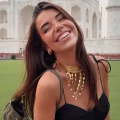 Elena Gortari sonríe feliz frente al Taj Mahal, luciendo un collar dorado y un vestido negro.