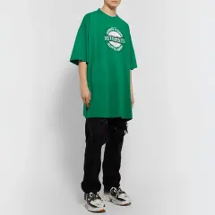 Camiseta verde de **oversize significado** con logo de Vetements, combinada con vaqueros negros rotos y zapatillas deportivas.