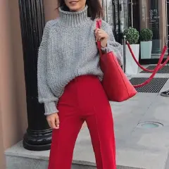 Chaqueta de punto gris y pantalones granate combinan a la perfección. Un bolso rojo vibrante completa el look.