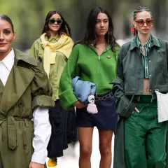 Cuatro mujeres lucen atuendos en tonos de verde oscuro, desde gabardinas hasta chaquetas y pantalones, creando un look monocromático y elegante.