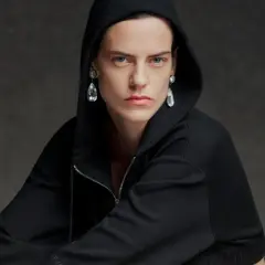 Modelo con sudadera negra con capucha y pendientes de lágrima, una visión audaz que evoca la estética de Pierpaolo Piccioli.