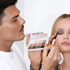 Mario Dedivanovic, maestro del maquillaje, aplica sombra de ojos a una modelo con una paleta neutra.