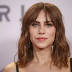 Mujer con cortes de pelo liso y fino, melena castaña con flequillo y piercing en la nariz.