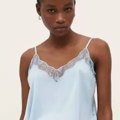 Un top lencero azul claro con detalles de encaje, ideal para lucir diferentes tipos de tops con estilo.