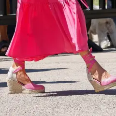 Pie de la Reina Letizia luciendo unas alpargatas de cuña rosas con cintas atadas al tobillo, combinadas con un vestido fucsia.
