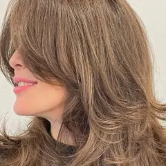 Cabello castaño con un corte mariposa, capas suaves que enmarcan el rostro y dan movimiento.