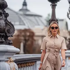 Alba Silva camina con elegancia por un puente parisino, luciendo un vestido camisero y gafas de sol.