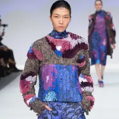 Modelo luce un diseño de upcycling que es una explosión de texturas y colores, con un suéter de tweed y apliques peludos sobre un vestido estampado floral.