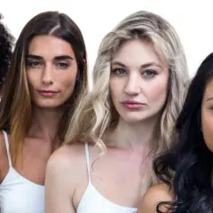 Cuatro mujeres de diferentes etnias, con labios en un suave color coral, posan juntas.