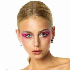 Mishel Gerzig con un audaz maquillaje de ojos rosa vibrante y pendientes llamativos.