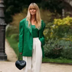 Mujer con traje verde brillante, top a juego y pantalones blancos. Muestra varios tipos de verde ropa en un look audaz.