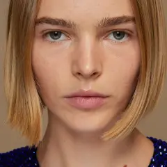 Primer plano de una mujer con un corte bob rubio y un vestido azul brillante.