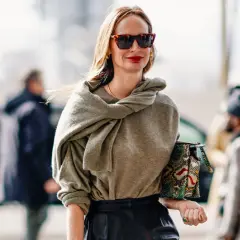 Mujer de unos 40 años con un look casual chic, gafas de sol, suéter gris y bolso estampado.