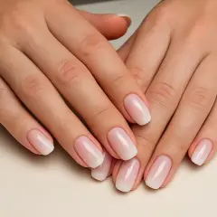 Manos con manicura rusa impecable, luciendo un degradado suave de rosa a blanco.