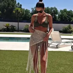 Paula Echevarría luce un bikini verde y una falda de crochet con flecos junto a la piscina, disfrutando del sol.