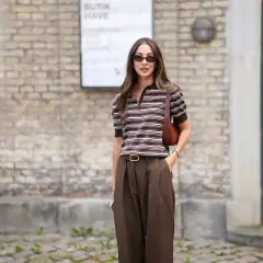 Mujer con estilo, combinando un pantalón marrón de tiro alto con una blusa a rayas marrones y blancas.