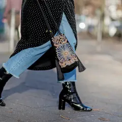 Estilo urbano: cómo combinar botines negros brillantes con jeans desgastados y un bolso bordado.