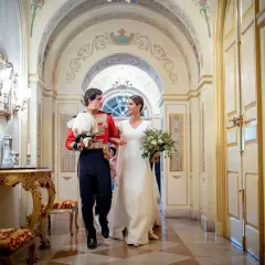 Sofía Palazuelo y su esposo, con traje de gala, caminan por un pasillo adornado, celebrando su boda.