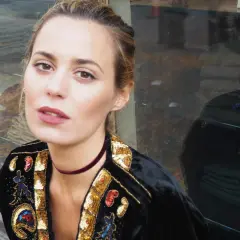 Claudia Ortiz Domecq, con un choker de terciopelo y chaqueta bordada, posa con mirada intensa frente a un escaparate.