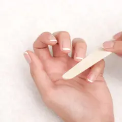 Manos limándose las uñas francesas. Una guía visual para saber como quitar uñas de gel.