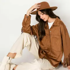 Mujer con sombrero y chaqueta de serraje que es suave y con flecos. Pantalones crema y botas blancas completan el look.