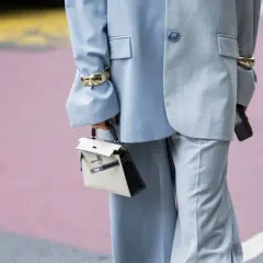 Traje gris con pantalones de pierna ancha (wide leg significado) y bolso blanco y negro.