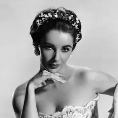 Elizabeth Taylor, con un tocado floral y un vestido de encaje, posa con elegancia.