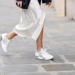 Elegante outfit: vestido blanco satinado con zapatillas deportivas blancas y plateadas.